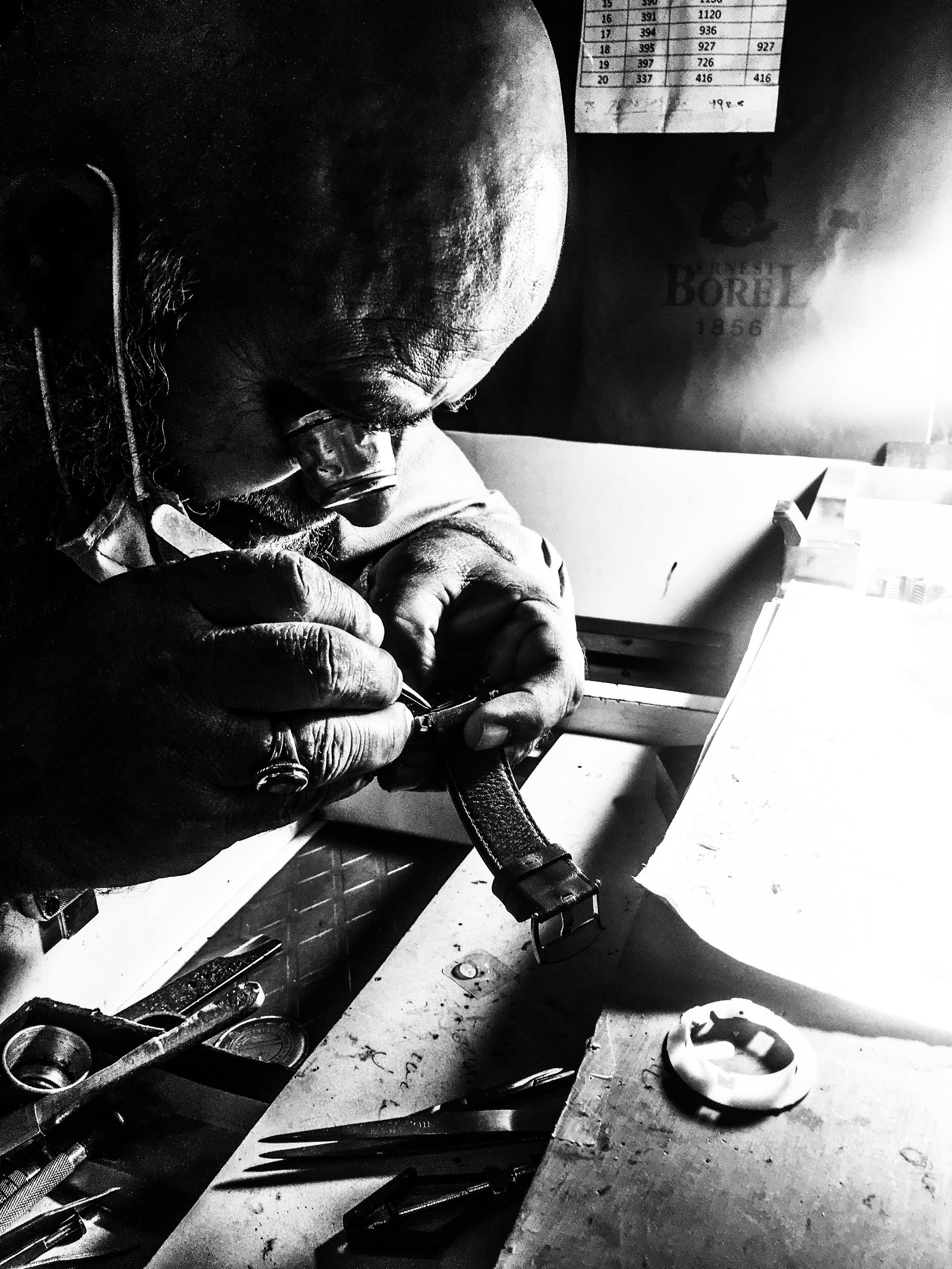 Un horloger au travail sur un mouvement de montre, concentration totale — artisanat à la main