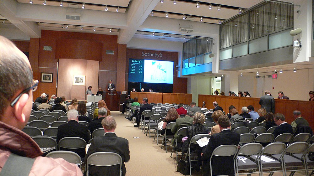 Intérieur de la salle des ventes de Sotheby's avec enchérisseurs présents, écrans en ligne et personnel téléphonique